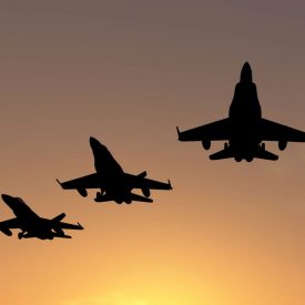 Military jets fly in formation with sunset in background